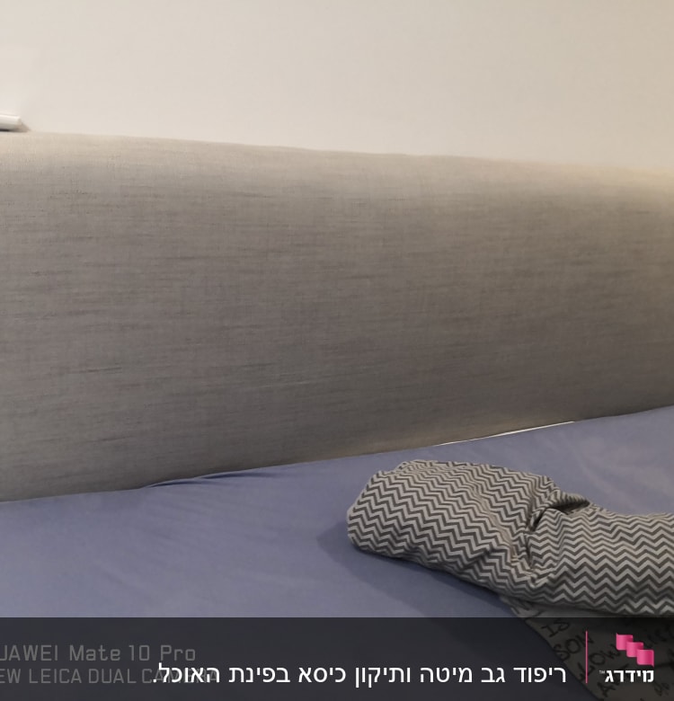 ראש מיטה מרופד בבד אפור עם כרית על המיטה